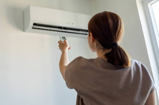 Woman turning on air conditioner with remote.
