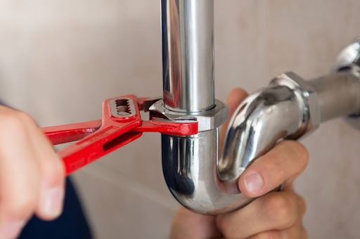 Close-up of a plumber fixing a pipe with a wrench.