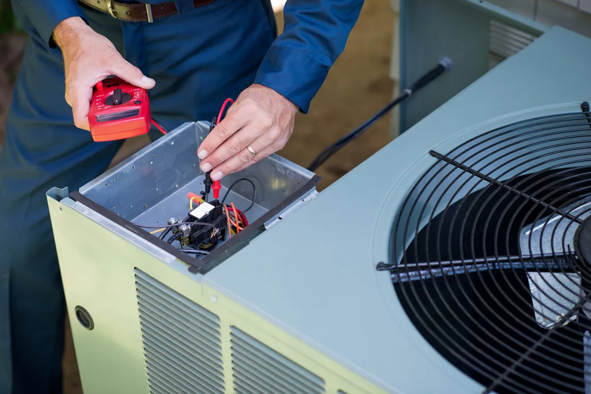 Conway air conditioner repairman in uniform using a volt meter.