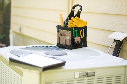 HVAC unit with technician’s tool bag and clipboard ready for maintenance outside a home.